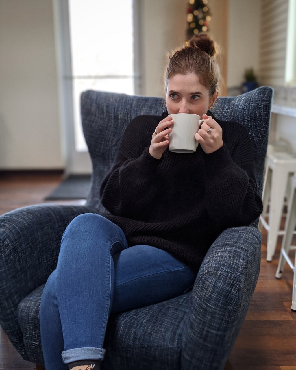 A photo of Callie Marsalisi sitting in an armchair drinking a cup of coffee.